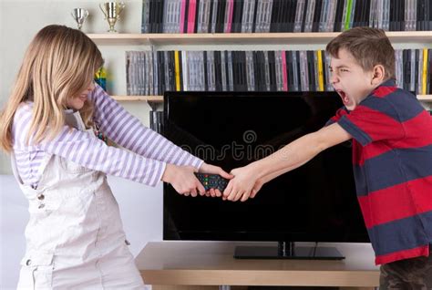 Siblings Fighting Over The Remote Control In Front Of The Tv Stock