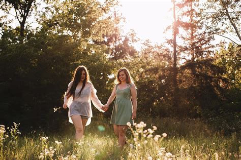 Happy Lesbian Couple Holding Hands While Walking In Forest