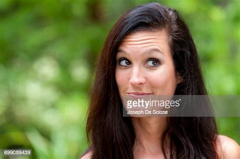 a 38 year old brunette woman outdoors making a face looking away from