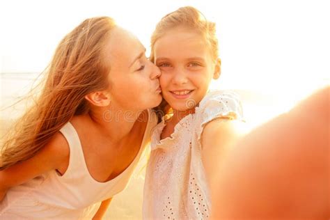 happy stylishly mother kiss daughter and taking selfie at sandy beach