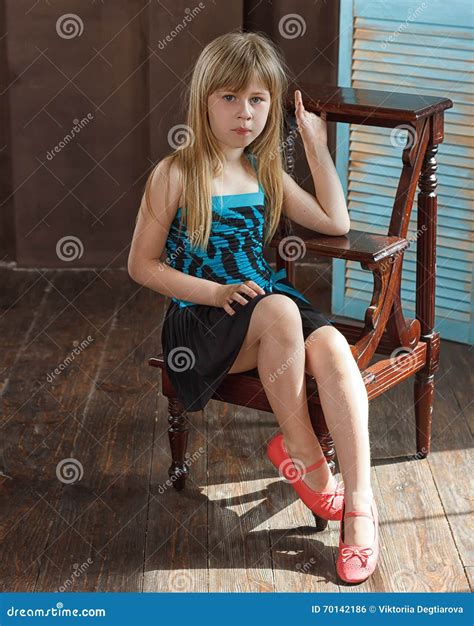 das maedchen  jahre alt im kleid sitzt auf einem stuhl stockfoto bild