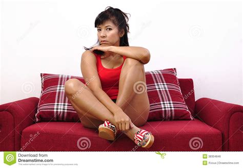 asian woman sitting on red sofa and facing the camera