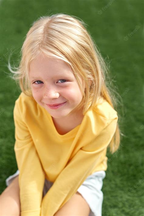 Premium Photo Pretty Blonde Girl Yellow T Shirt Sitting On Green