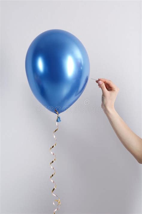 woman piercing inflated condom with pin on background
