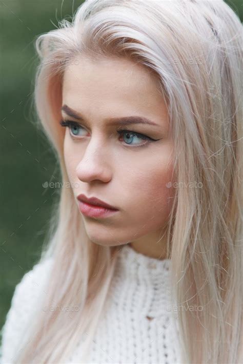 Portrait Of A Beautiful Serious Blonde Girl In A White Knitted Sweater