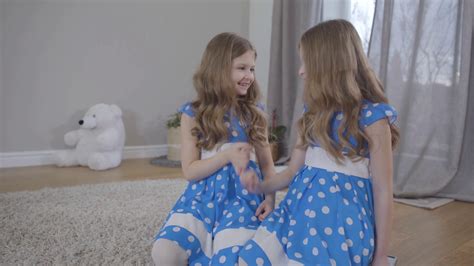 Two Positive Caucasian Twin Sisters In Elegant Blue Dotted Dresses