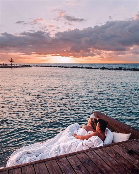 two people are laying on a boat in the water at sunset with one person