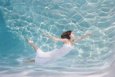 Underwater View Of Caucasian Woman In Dress Swimming In Pool Stock