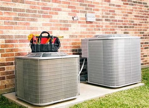 air conditioners sitting      front   brick wall  green grass