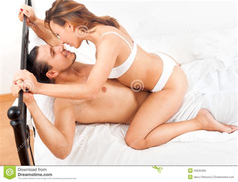 Happy Adult Couple Having Sex On Bed In Bedroom Interior