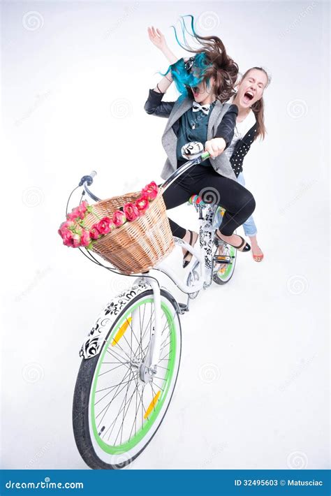 Two Girls Riding A Bike Making Funny Faces On Bluish Background Stock