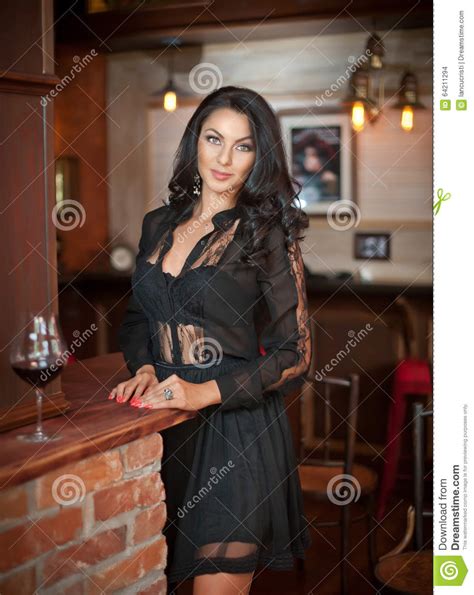 beautiful sensual woman standing with glass of wine on red