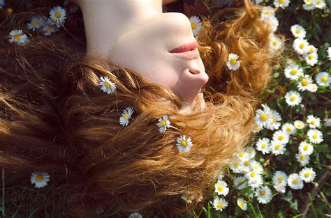 redhead girl lying in the daisies by stocksy contributor marija