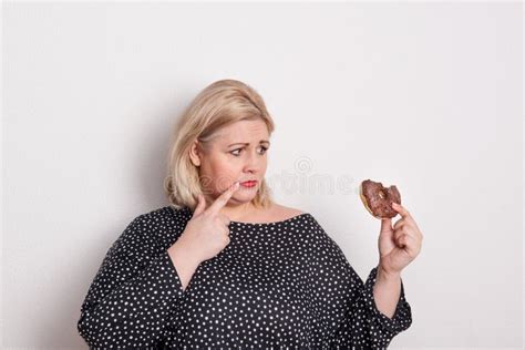 An Attractive Overweight Woman Eating A Donut Feeling Guilty Stock