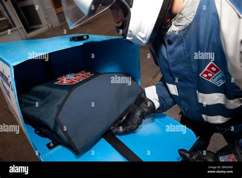 dominos pizza delivery driver loading  moped  freshly cooked hot pizza stock photo