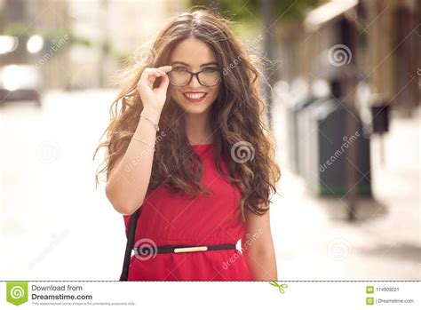 beautiful girl with long hair and glasses smiling in street stock image