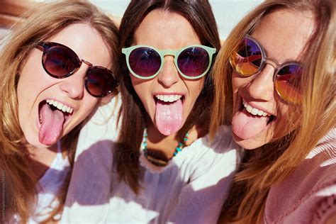 three friends sticking out tongues by stocksy contributor guille