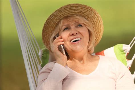 Mature Woman Talking By Mobile Phone While Resting Outdoors Stock Image