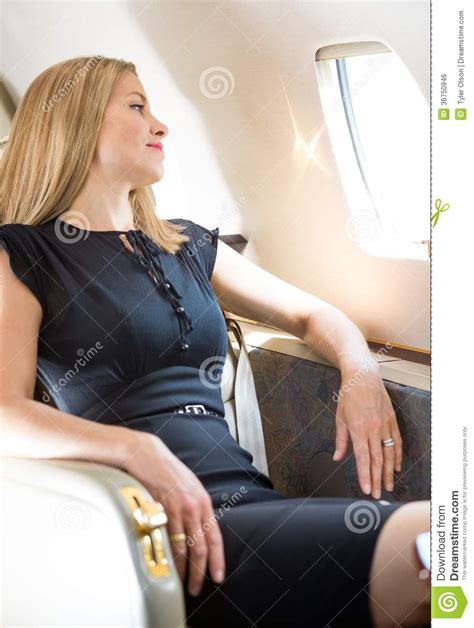 rich woman looking through private jet s window royalty