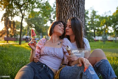 beautiful serene lesbian couple enjoying ice cream at a park high res