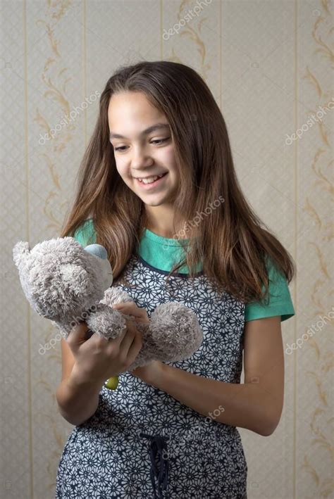 niña de 11 año de edad feliz sosteniendo un oso de peluche y le miraba con amor — foto de stock