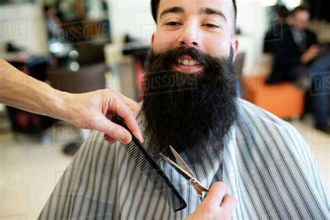 Hairdresser Trimming Customer S Beard In Barber Shop