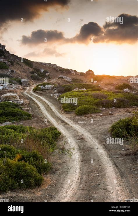 single lane curved rural country road crossing   hill   dramatic sunset