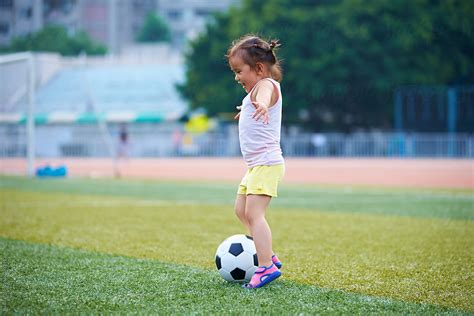 little asian or chinese girl playing football outdoor in the football