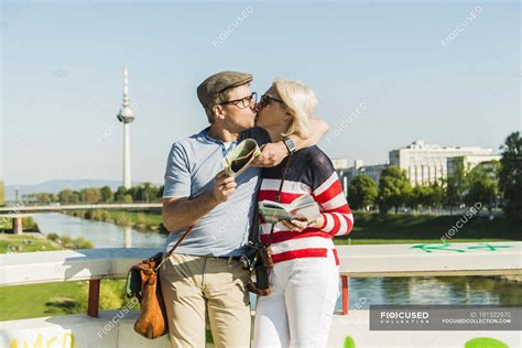 Germany Mannheim Mature Couple Taking City Break Kissing On Bridge