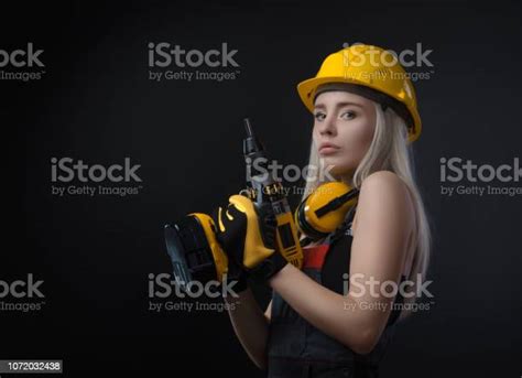 Girl In Construction Clothes And Protective Equipment Posing With A