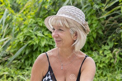portrait of a elderly woman 60 65 years old in a straw hat and swimsuit