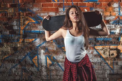 beautiful asian teen girl with skate board on shouldres outdoors urban lifestyle stock
