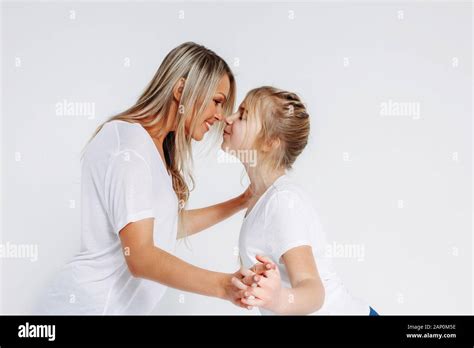 Real Mom And Daughter In White T Shirts And Jeans Kissing Isolated On