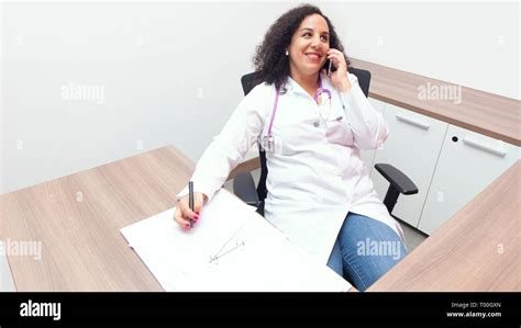 Female Latin Female Doctor Sitting Smiling Relax In Her Consulting Room