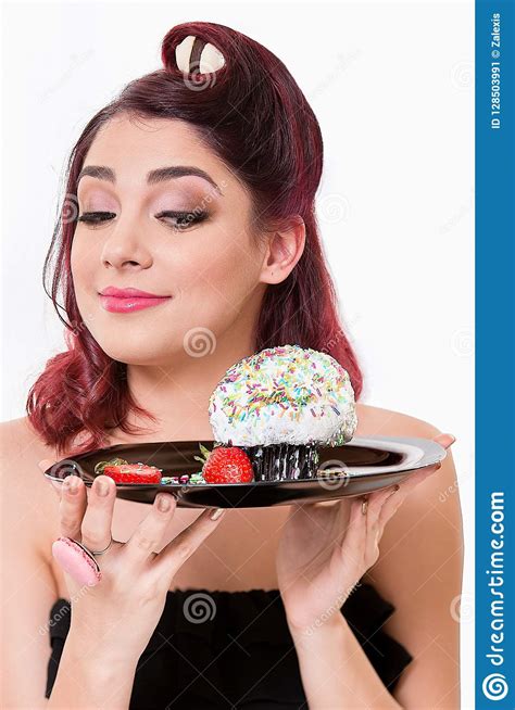beautiful redhead woman smiling and looking at the cupcake