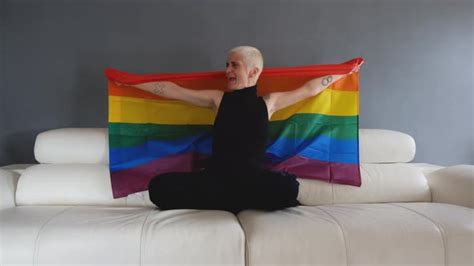 lesbian having fun and waving lgbt flag at home while sitting on white