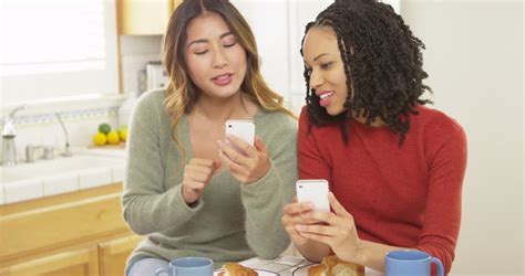 African American And Asian Friends Using Mobile Phones And