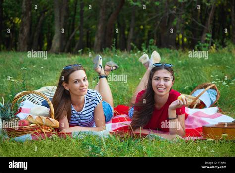 Two Beautiful Girls Rest On A Picnic In The Forest And Having Fun Stock