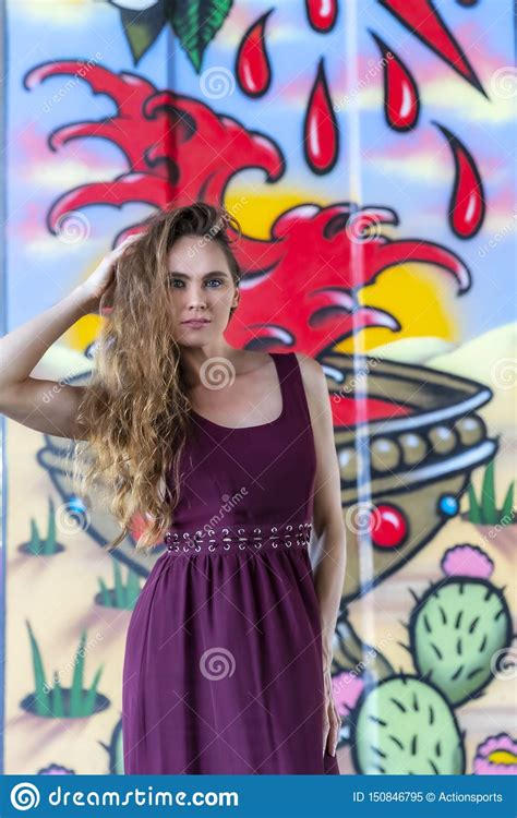 Lovely Brunette Model Posing Outdoors Against Graffiti Editorial Image