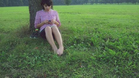 woman talking on smart phone outdoors on grass girl laughing having a conversation on mobile