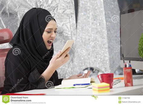 moslimvrouwelijke werknemer die op de telefoon spreken terwijl het werken met laptop computer