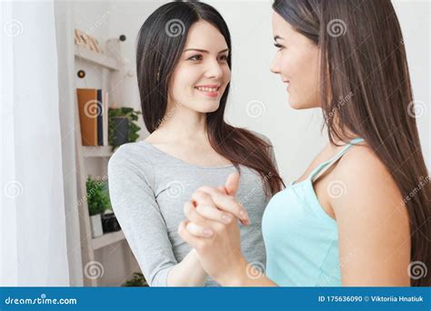 Lesbian Couple In Bedroom At Home Standing Holding Hands Smiling Happy