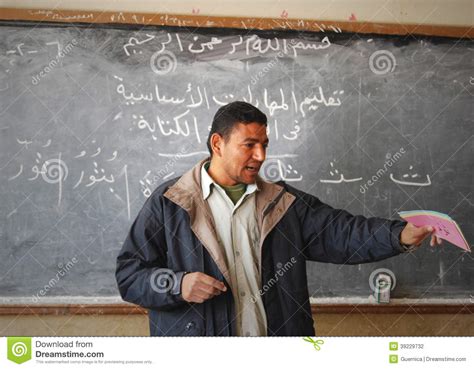 Male Teacher In Classroom Explaining On Blackboard
