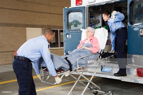 ambulanciers paramédicaux mettant senior femme en ambulance photo