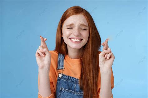redheaded girl hopes for miracle with closed eyes and crossed fingers