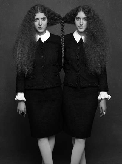 two women with long hair standing in front of a black and white photo