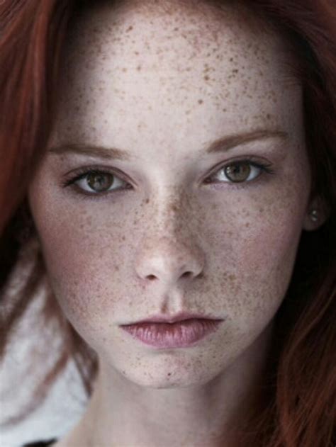 A Woman With Freckles On Her Face Is Posing For The Camera And Has Long