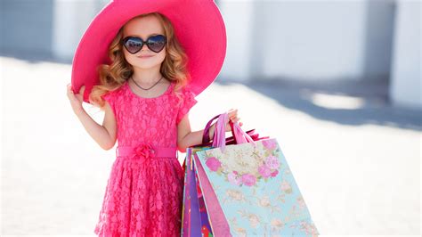 small cute girl is wearing pink dress and hat having bags