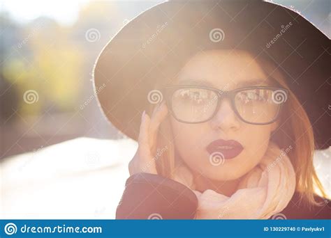 urban portrait of lovely blonde model with red lips wearing glasses and