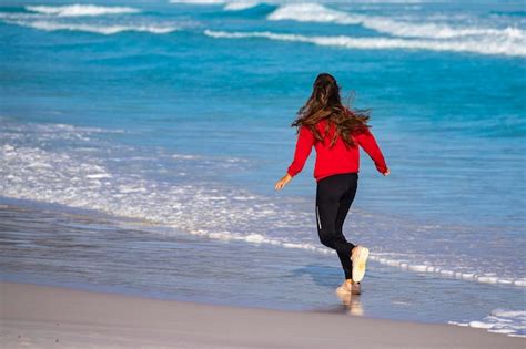 Premium Photo Back View Of A Long Haired Girl Running Along The Ocean
